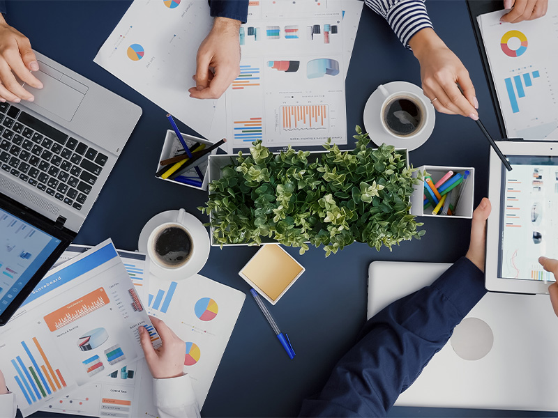 Personen sitzen an einem Tisch und schauen sich Diagramme an