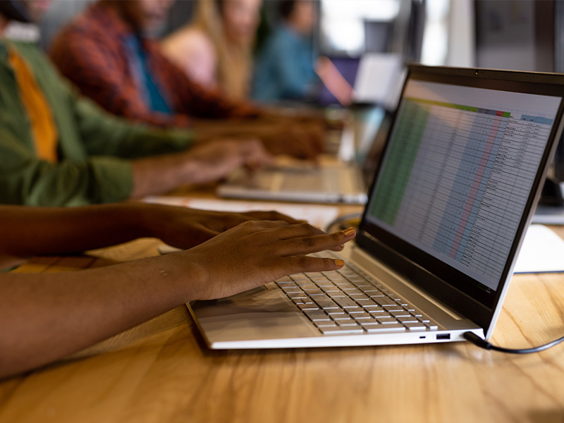 Teilnehmende in einer Excel Grundlagen Schulung arbeiten gemeinsam an Laptops