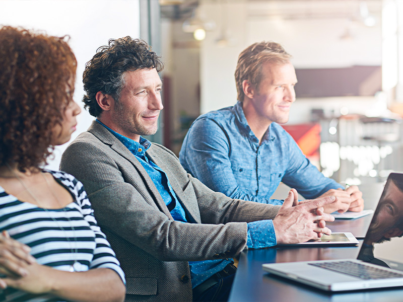 Teilnehmende in einer Excel Grundlagen Schulung arbeiten gemeinsam an Laptops